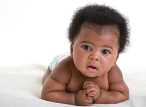 African American baby in diaper on tummy.