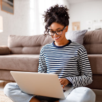 Woman in striped shirt sitting on the floor using a laptop